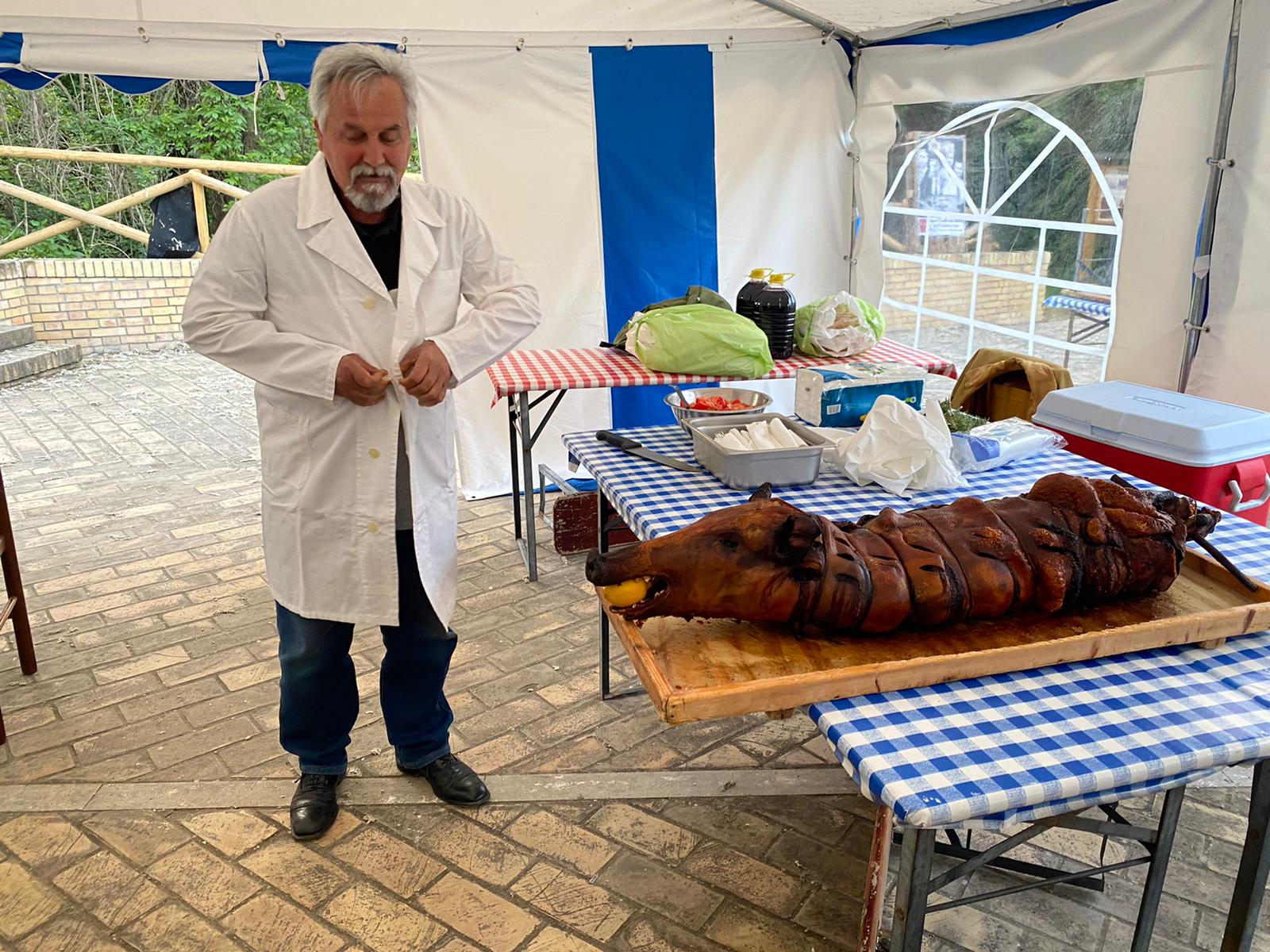 Fotografia contemporanea a Ripa Teatina con artigiano in camice accanto alla porchetta Bucci, testimonianza della continuita del mestiere.